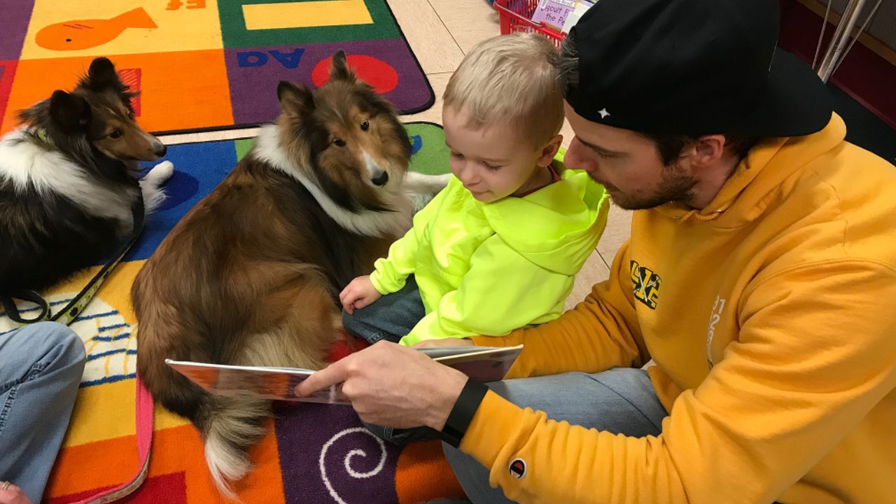 adult an child reading to therapy dogs