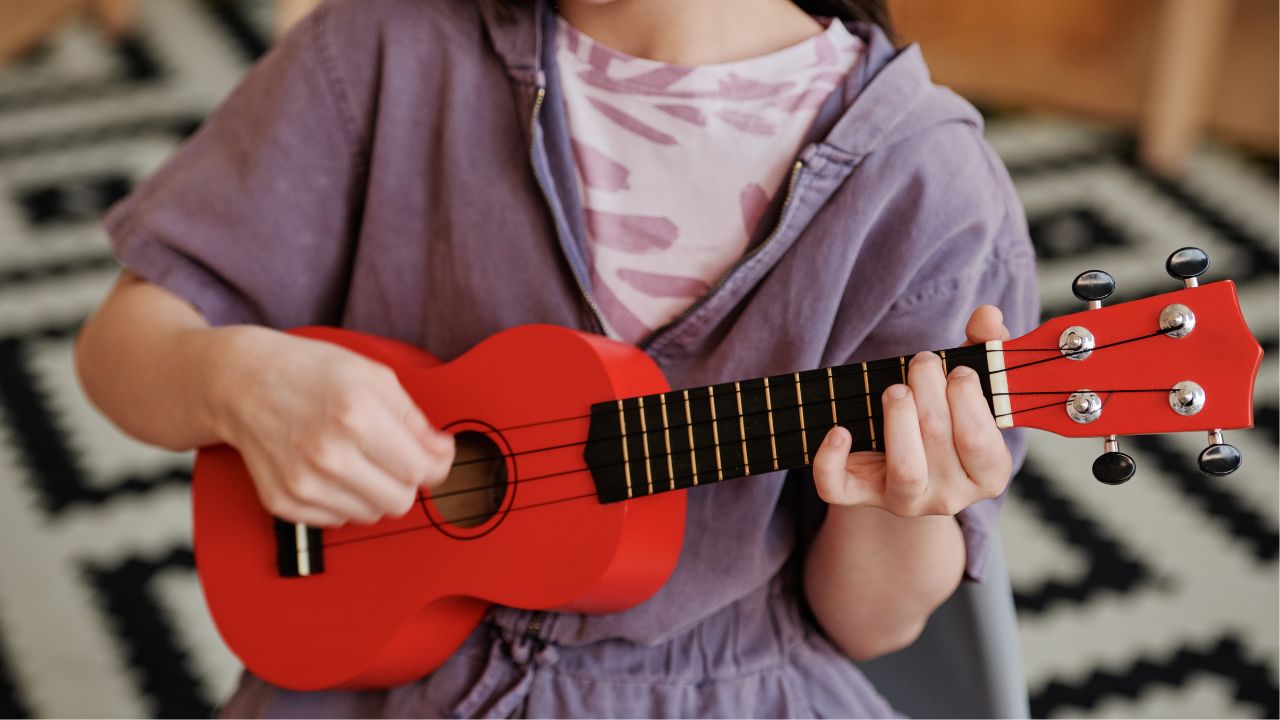 young child playing a ukulele