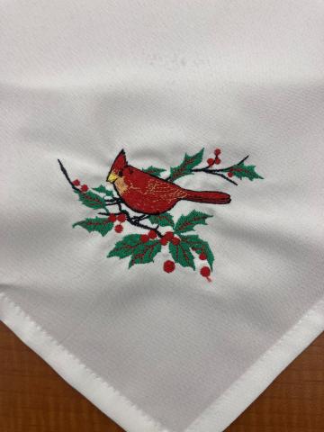 Napkin with cardinal and holly embroidered onto the corner