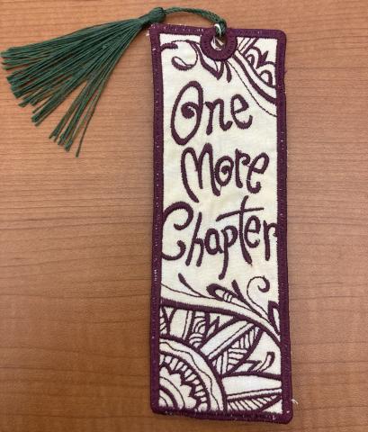 Fabric bookmark embroidered with "One More Chapter"