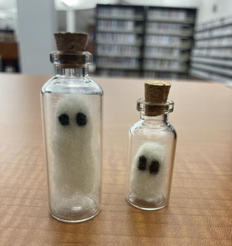 Two needle felted ghosts in glass bottles.