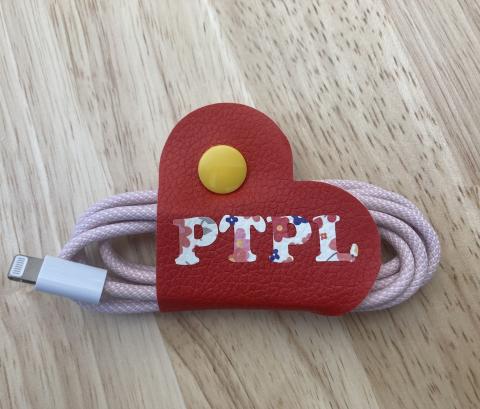 Faux leather cord minder with the letters "PTPL"