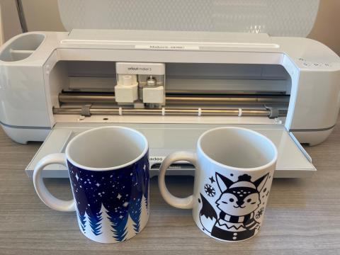 Two mugs in front of Cricut machine