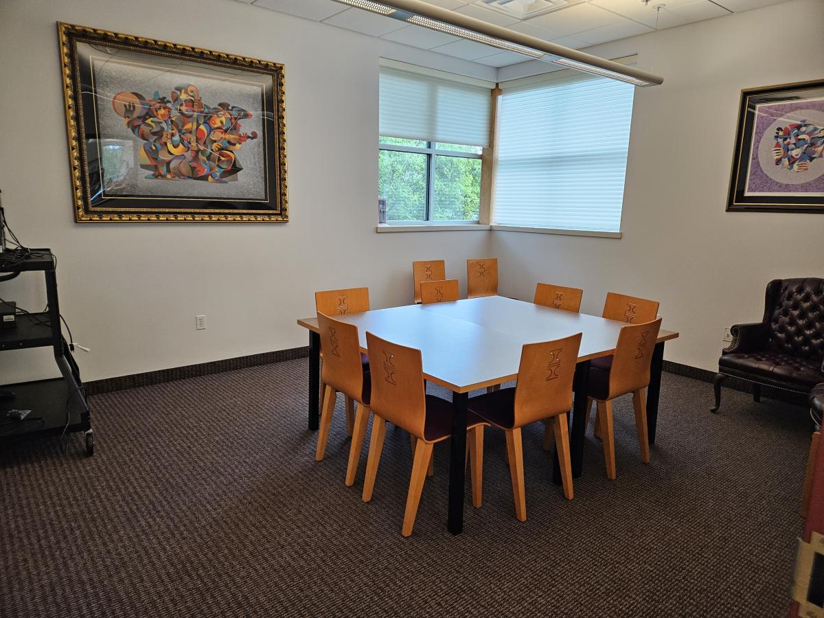 small conference room setup with large table and 8 wooden chairs