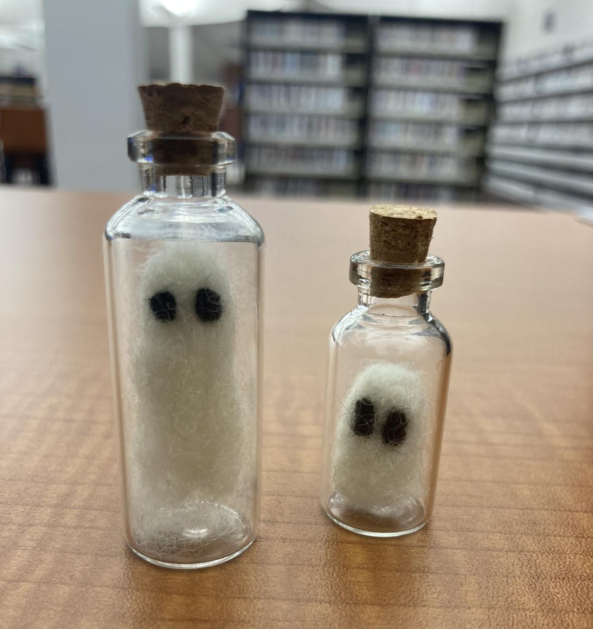 Two needle felted ghosts in glass bottles. 