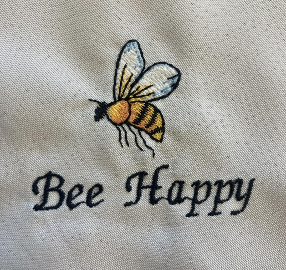 Napkin embroidered with a bee and the words "Bee Happy"